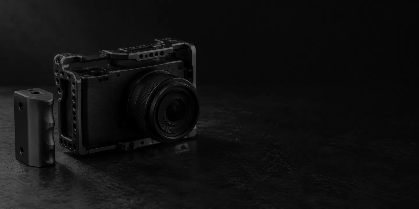 Greyscale conceptual compact camera in a metal cage with a detached grip on a dark desk.